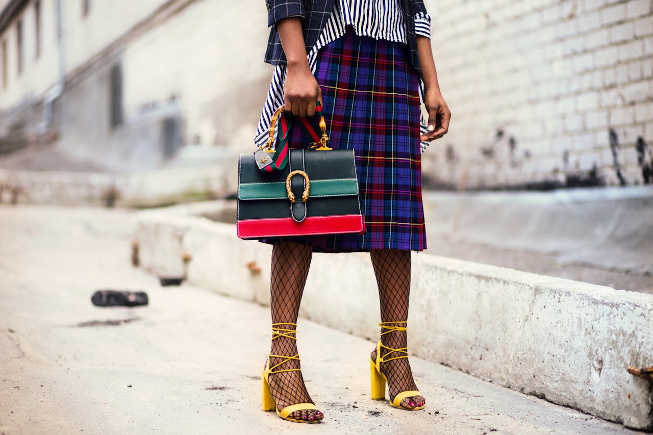 our-services-1 Fashion-forward outfit with plaid skirt and colorful handbag in urban setting.